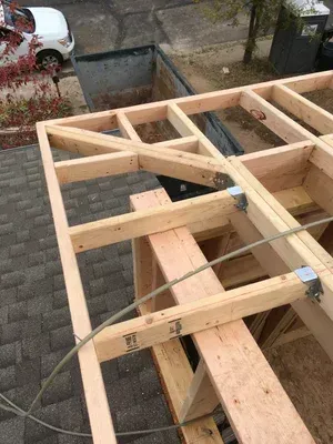 Wooden roof framing with beams and braces, viewed from above on a construction site.