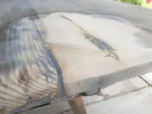 Cracked concrete sidewalk with a large damaged patch and dark stains on the surface