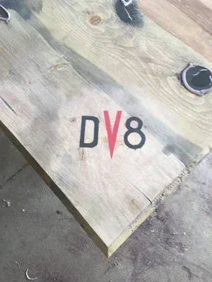 Close-up of a weathered wooden surface with a DV8 logo in black and red.