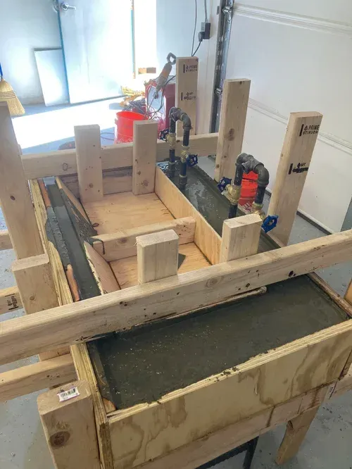 Wooden construction formwork with concrete being poured in a workshop-like setting