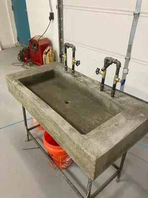 Concrete utility sink in a garage with two faucets and a fire extinguisher nearby