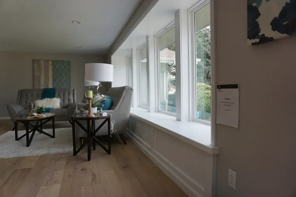 Bright living room with a sofa, coffee tables, lamp, and large windows letting in daylight