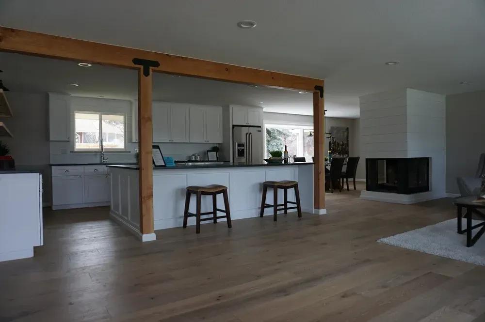 Open-plan living room with kitchen pass-through, wood floors, stools, and a fireplace