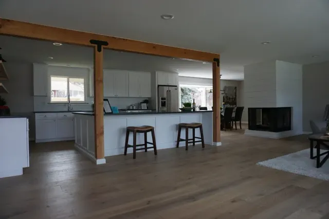 Open-plan living room with kitchen pass-through, wood floors, stools, and a fireplace