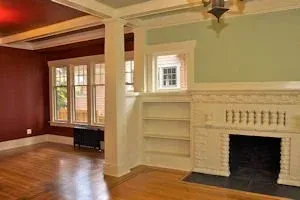 Spacious living room with hardwood floors, red and green walls, built-in shelves, and a white fireplace
