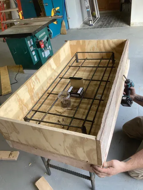 Wooden box with black metal frame inside, being held in a workshop.