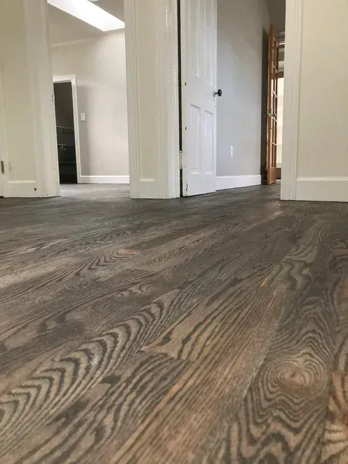Low-angle view of a hallway with gray wood flooring and white doors.