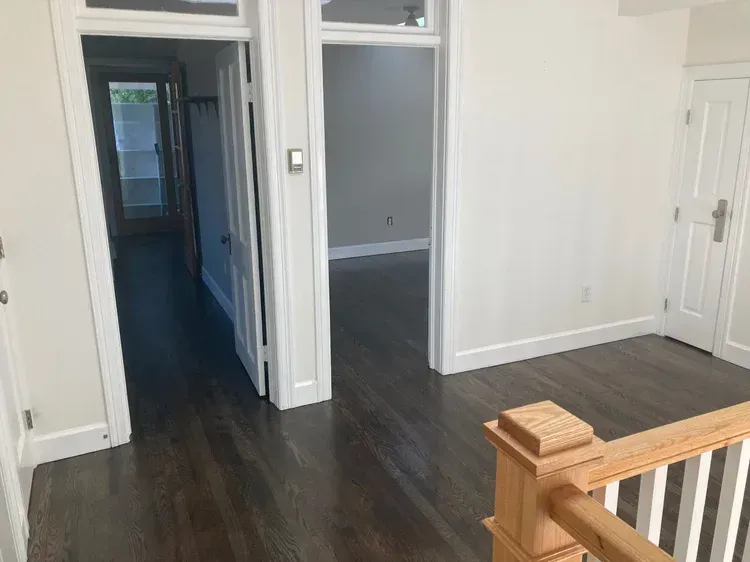 Empty hallway with dark wood floors and white doors in a bright apartment interior