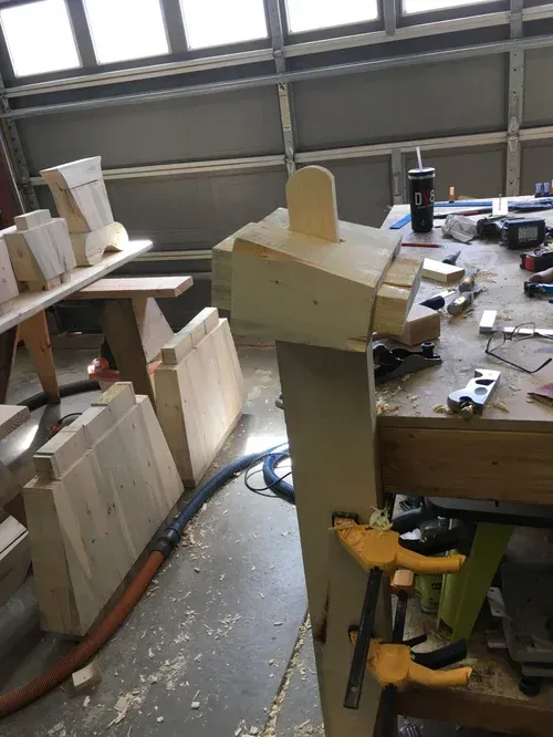 Workshop bench with woodworking jigs, clamps, and wood pieces near a garage door.