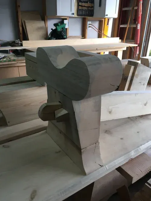 Unfinished wooden bench or chair frame with a carved backrest in a workshop interior