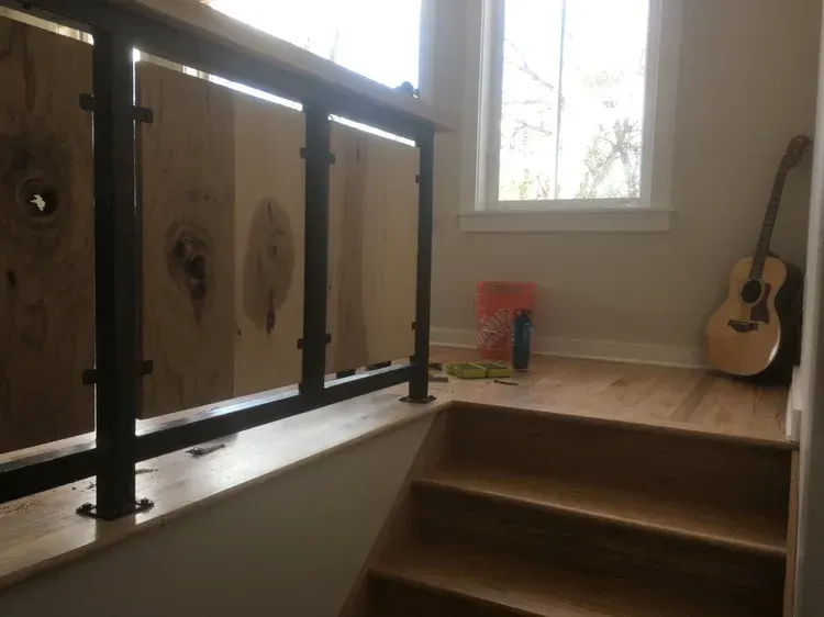 Indoor staircase with wooden railings, window light, and an acoustic guitar on the right wall.