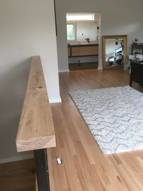 Minimalist living room with wooden bench, light rug, and mirror leaning against the wall
