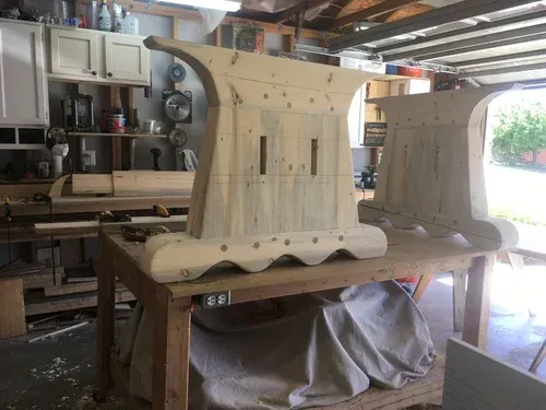 Wooden furniture pieces in a workshop, unfinished and clamped on a workbench.