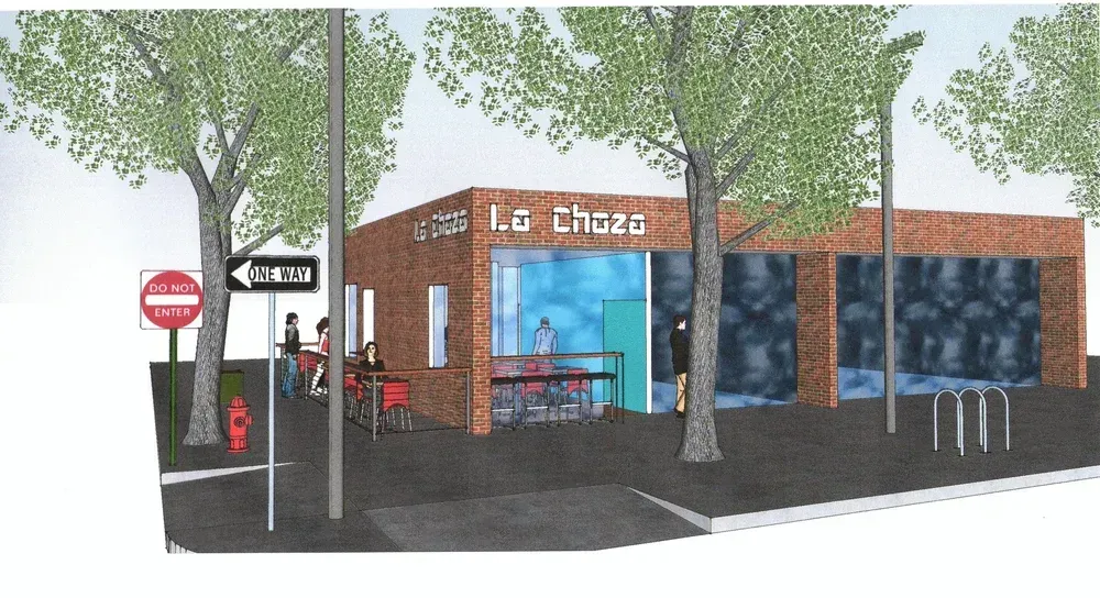 Brick café storefront with blue window panels, trees, bike racks, and a stop sign on the sidewalk
