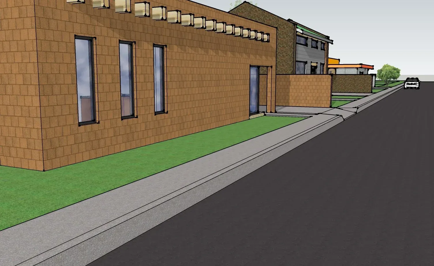Brick building beside empty sidewalk and road, with small covered entrance and grass strip.