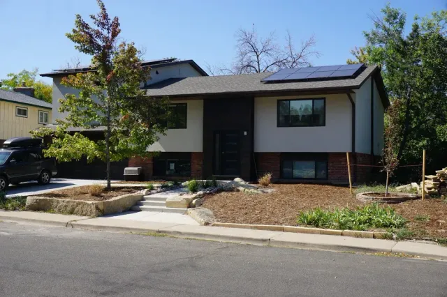 Modern suburban house with white and dark siding, front yard, and driveway on a sunny day