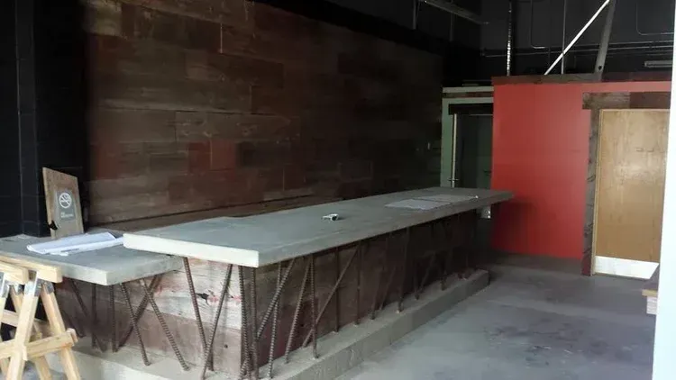 Folded tables stacked in a dim storage room beside a red wall and door