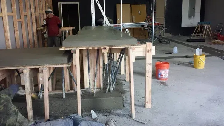 Construction site with unfinished concrete countertops, wood framing, and tools in an indoor workspace