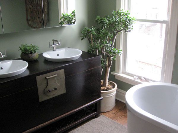 Modern bathroom with double sink vanity, potted plant, and a white bathtub by a window