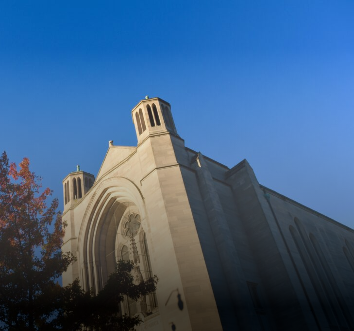Beige stone building with arched windows and two small towers against a clear blue sky.