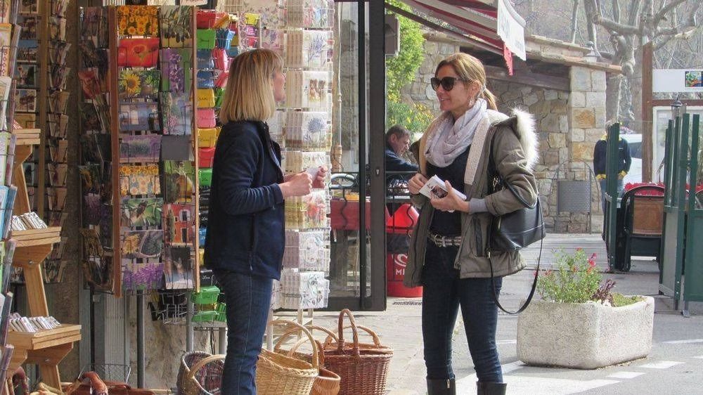 Deux femmes se tiennent devant un magasin et discutent entre elles.