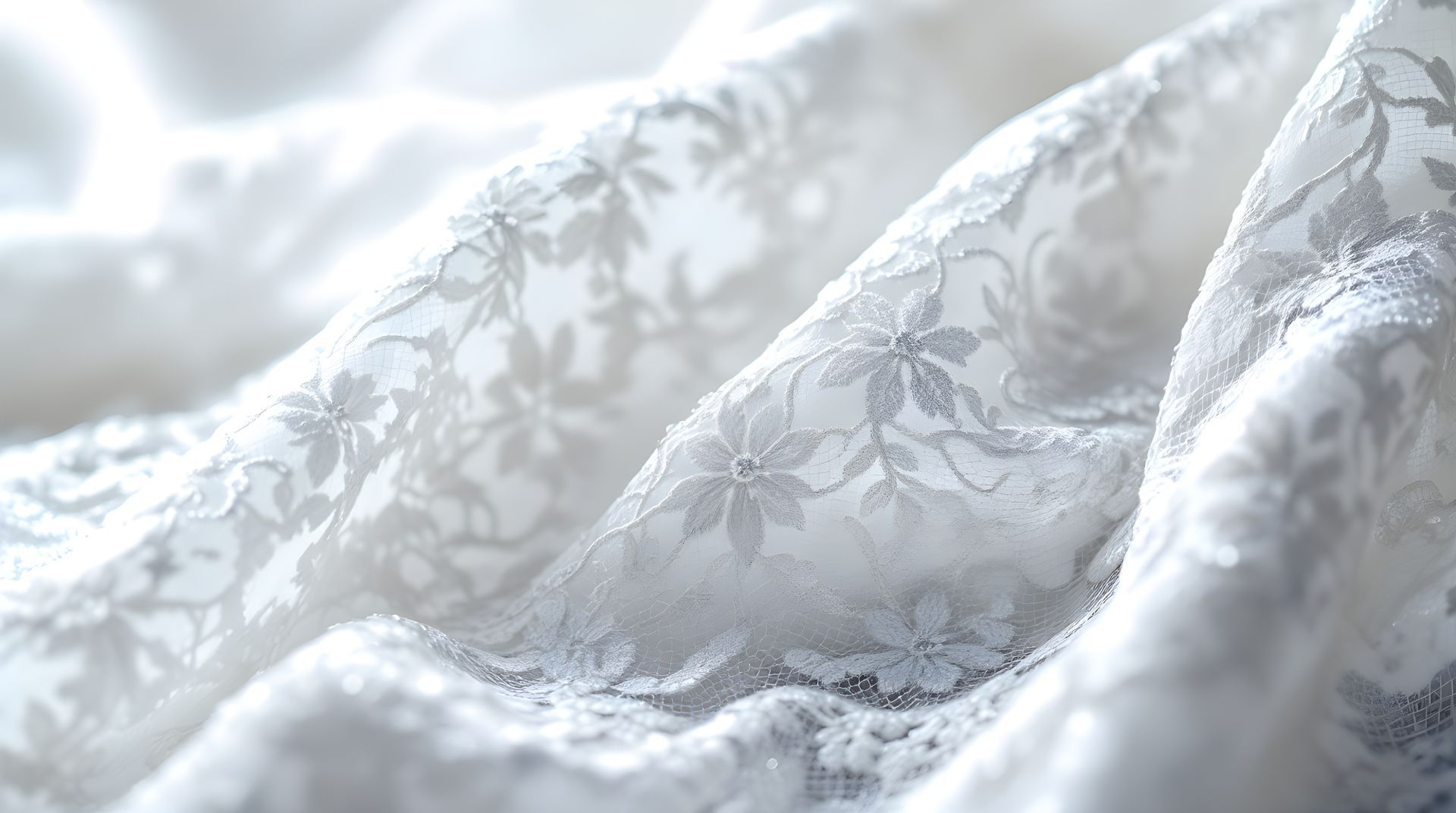 White floral lace fabric draped in soft folds with a delicate embossed pattern