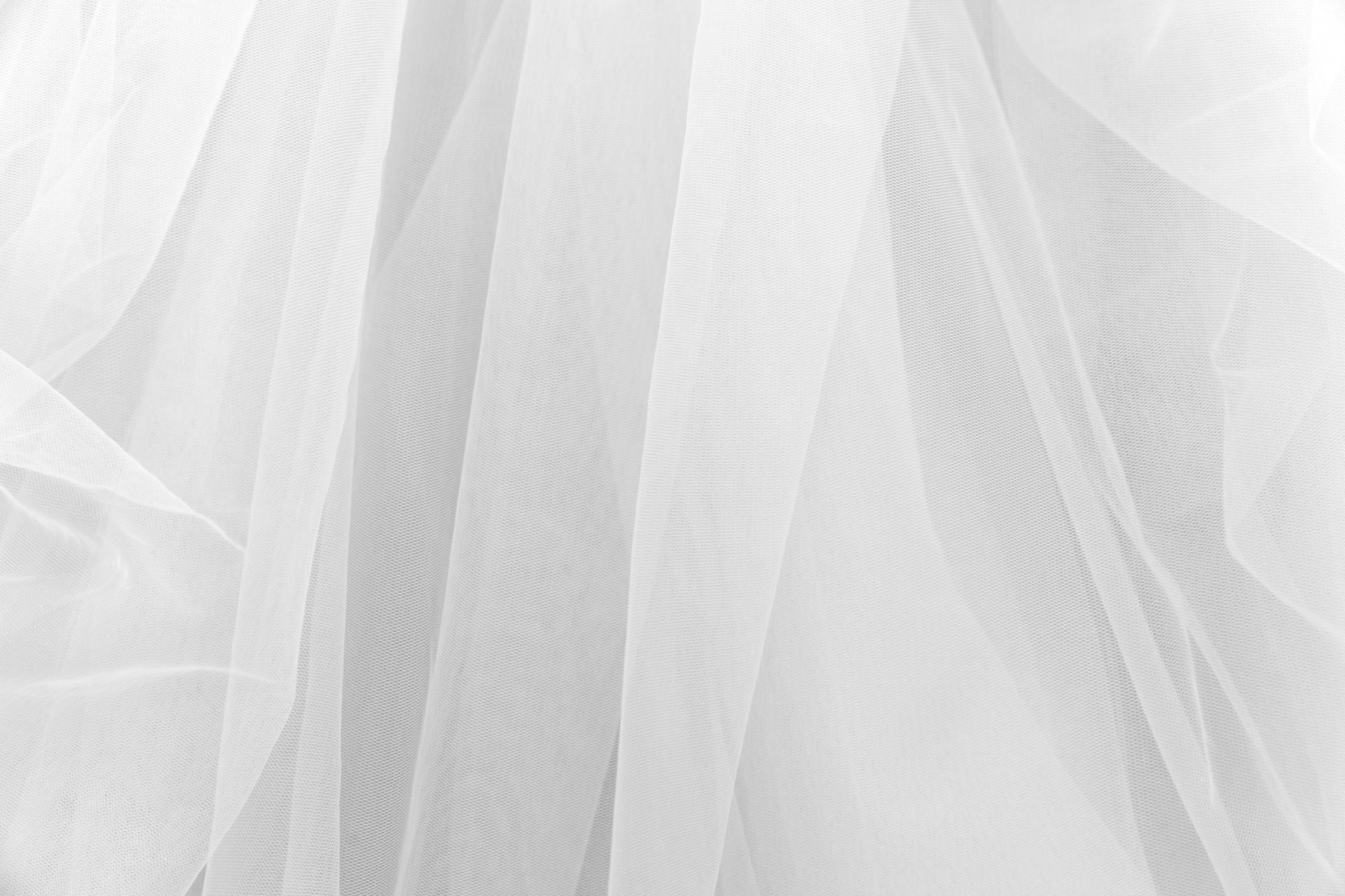 White sheer fabric draped in soft folds, creating a delicate textured pattern