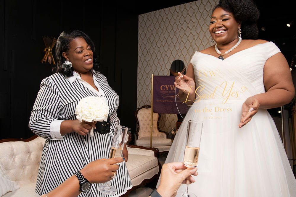 Two women smiling and holding champagne glasses at a celebration event