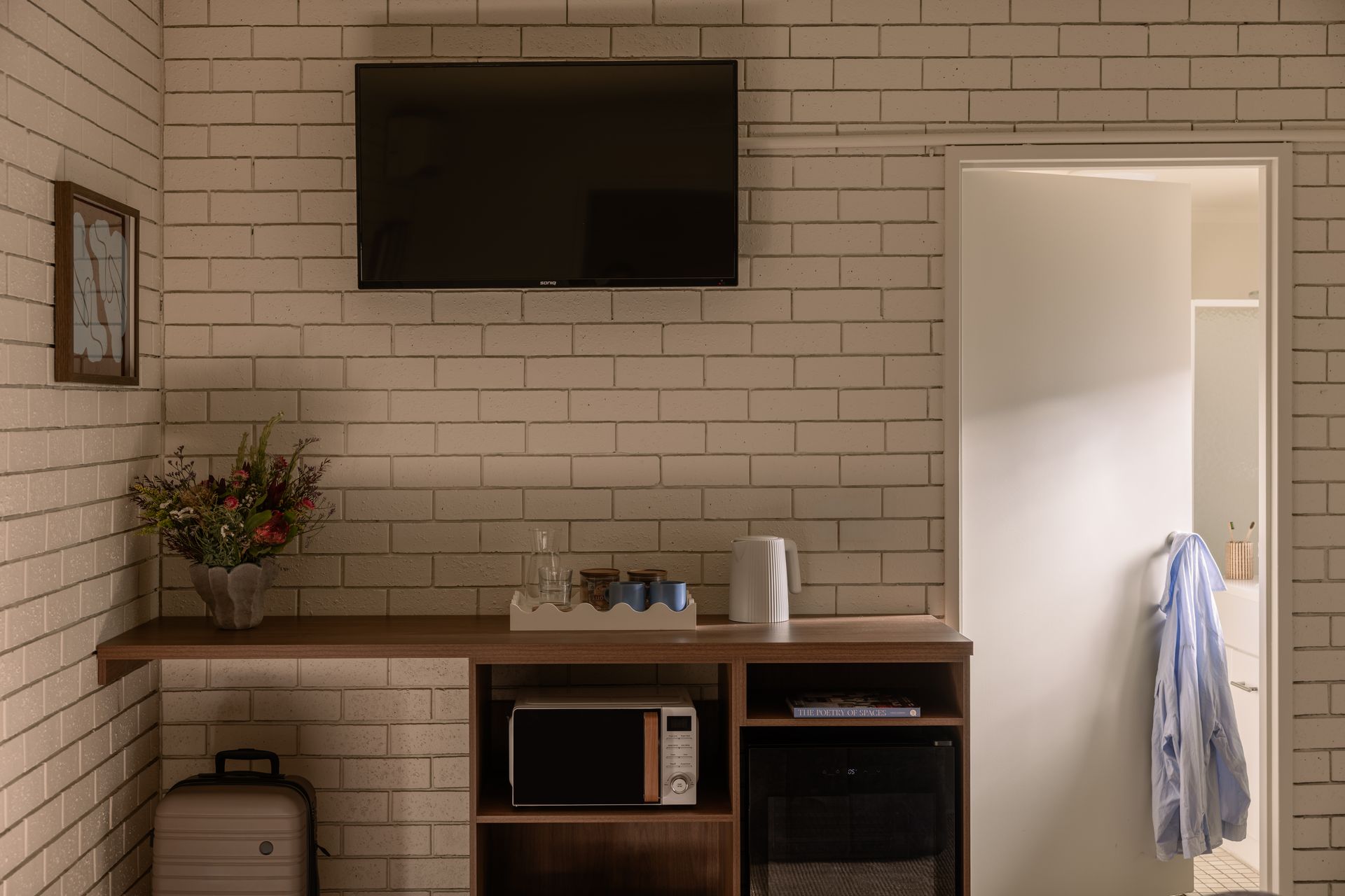 Living room with a wall-mounted TV, console table, and open doorway with a robe hanging nearby.