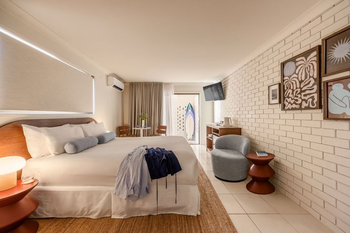 Cozy bedroom with bed, warm lamps, woven rug, and brick accent wall