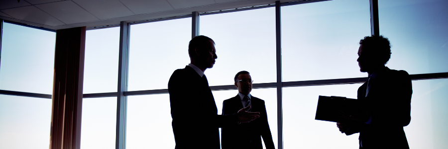 A group of business people standing in front of a window