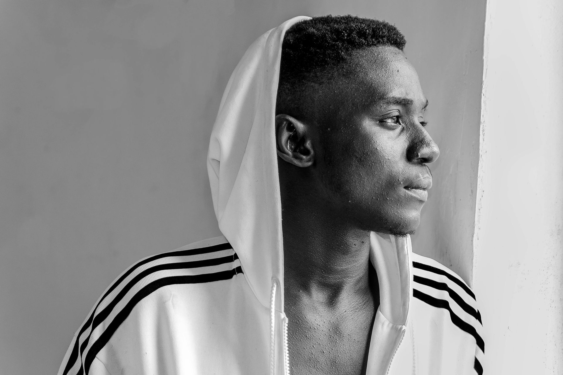 A black and white photo of a man wearing a white hoodie.