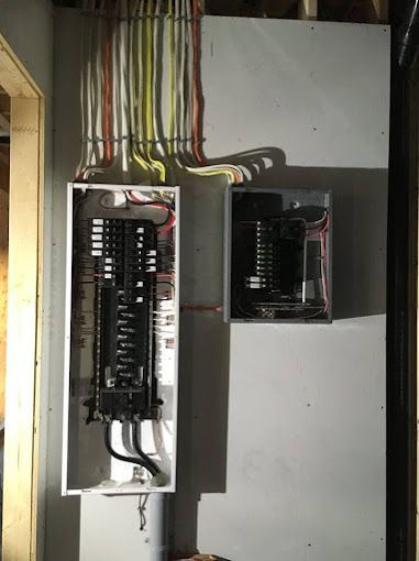 Open electrical breaker panels with exposed wiring in a utility closet