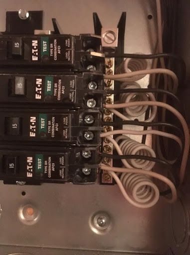 Electrical breaker panel with four black Eaton breakers and white wires connected.