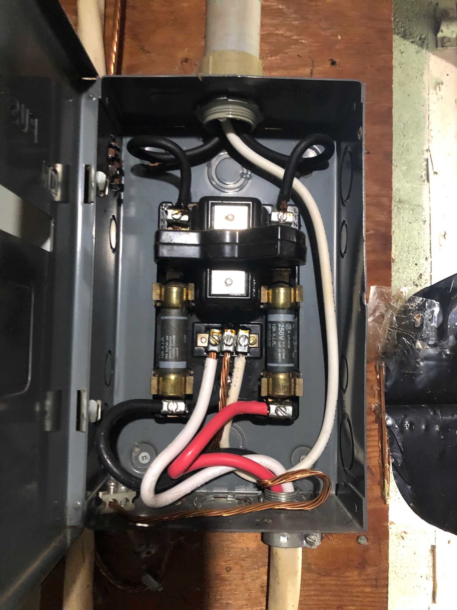 Open electrical control box with relays, wiring, and fuse blocks inside a black metal enclosure