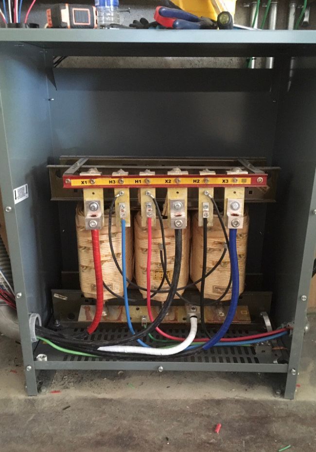 Electrical breaker panel with wires and bus bars inside a dark cabinet