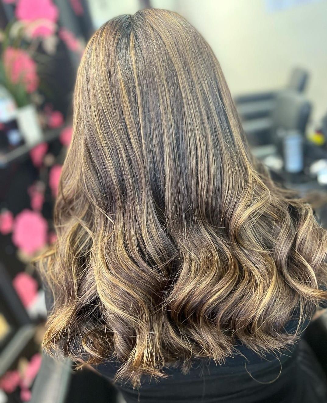 Close-up of shoulder-length wavy brown hair with blonde highlights in a salon setting