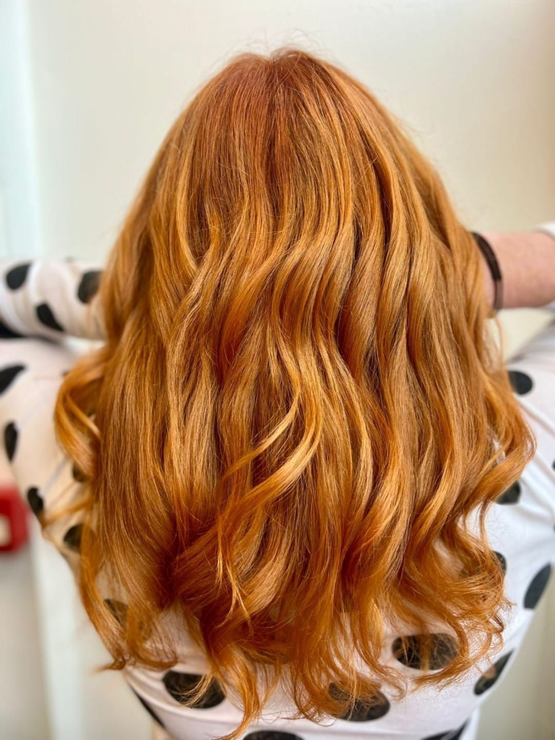 Copper-red wavy hair seen from behind against a light background