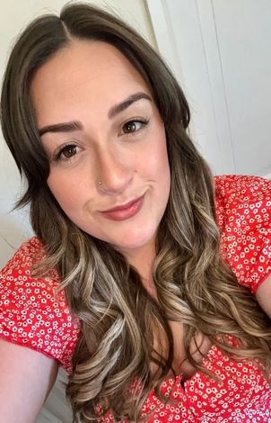 Woman in a red floral top smiling at the camera indoors