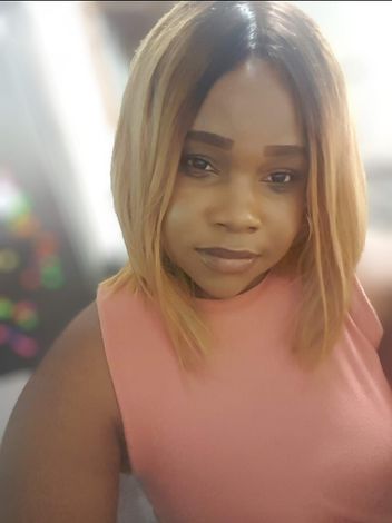 Portrait of a person in a pink sleeveless top, facing the camera with a neutral expression.