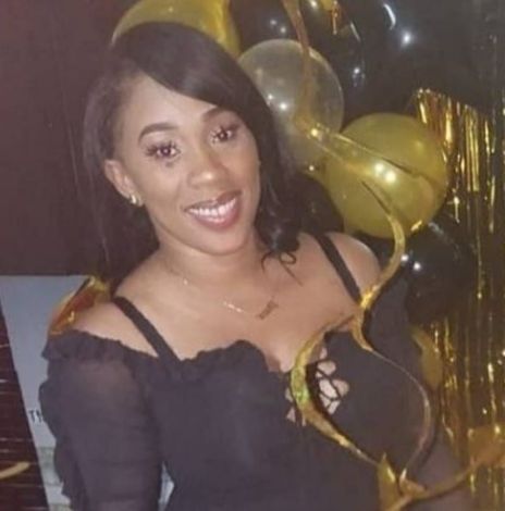 Smiling woman in a black dress posing with gold and black balloons at a party