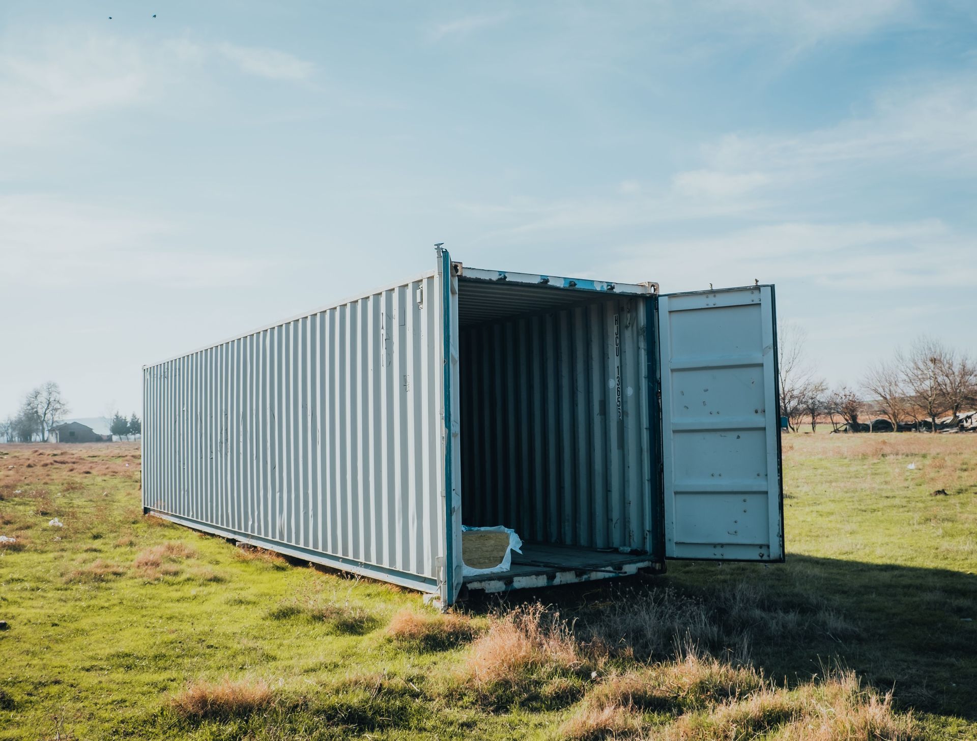 Contenedor de transporte abierto en un campo de hierba bajo un cielo despejado