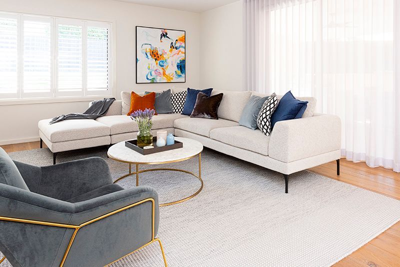 A living room with a couch , chair , coffee table and painting on the wall.