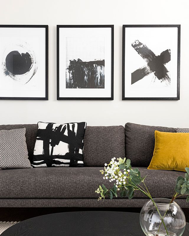 A living room with a couch and three paintings on the wall