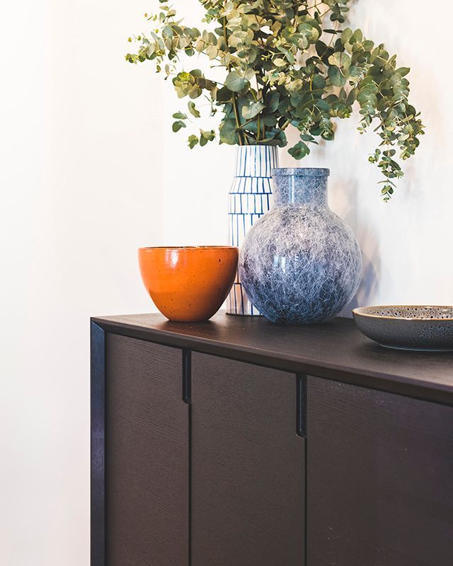 A dresser with two vases and a bowl on it