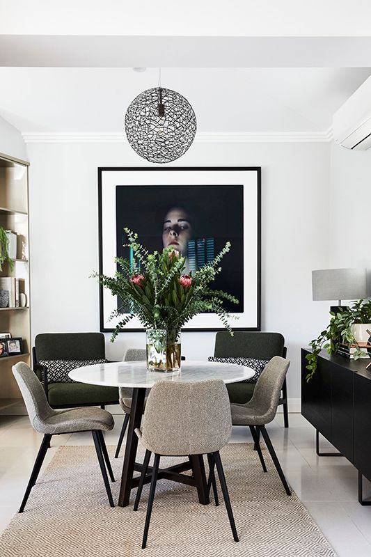 A dining room with a table and chairs and a picture on the wall.