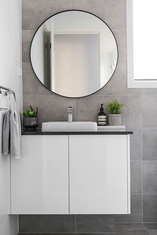 A bathroom with a sink and a round mirror.