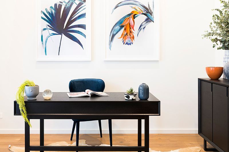 There are two paintings on the wall above the desk.