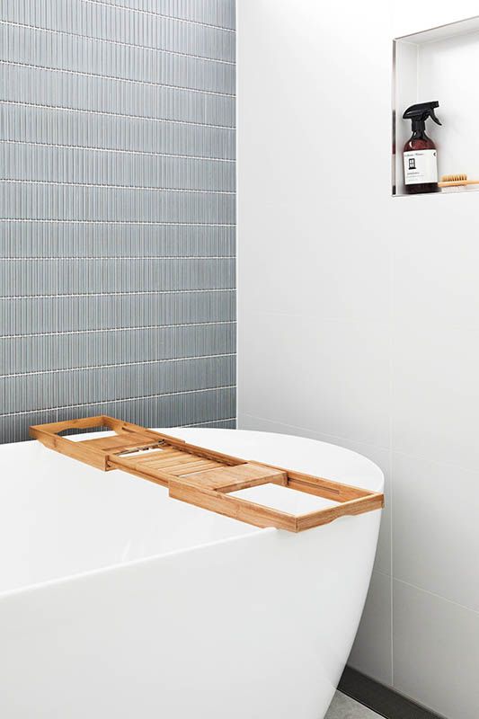 A bathtub with a wooden tray on top of it in a bathroom.