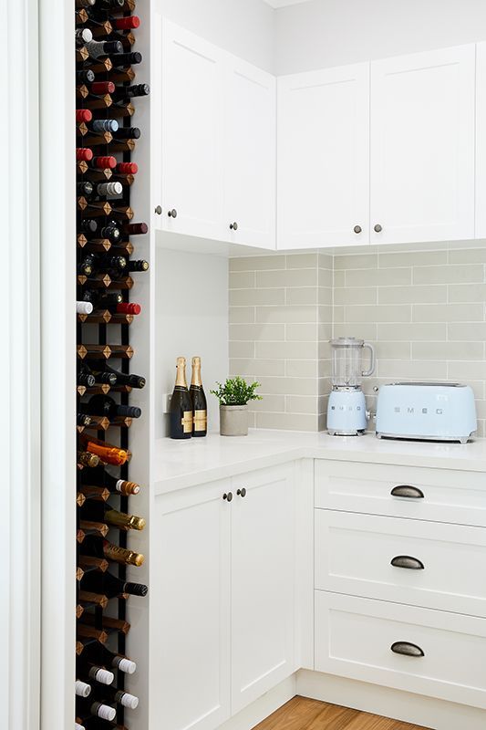 A kitchen with white cabinets and a wine rack filled with wine bottles.
